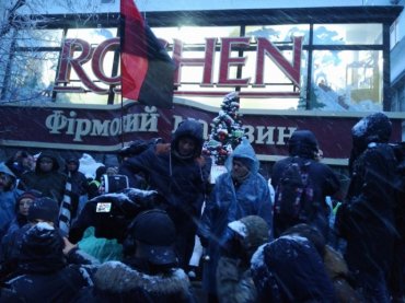 Участники марша забрасывают снегом магазин Roshen под изолятором СБУ