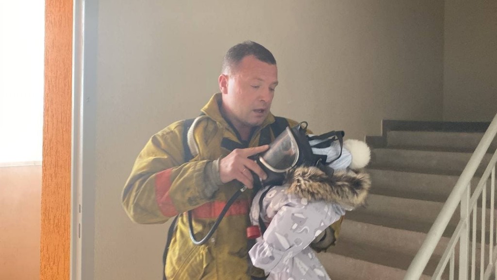 Спасатель накрыл маской с кислородом ребенка во время эвакуации