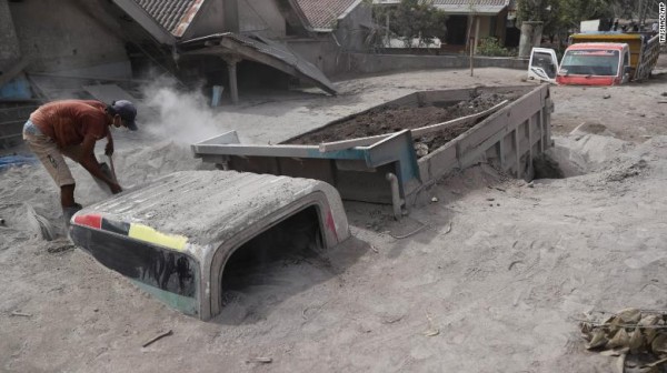 Житель деревни пытается откопать свой грузовик, засыпанный вулканическим пеплом.