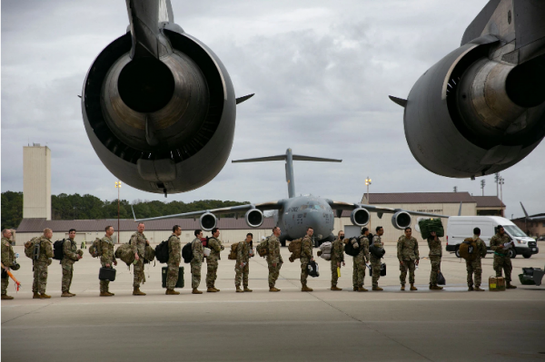 Солдаты выстраиваются в очередь на взлетно-посадочной полосе, ожидая посадки на транспортные самолеты.
