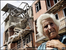 Женщина на фоне разрушенного дома в Гори