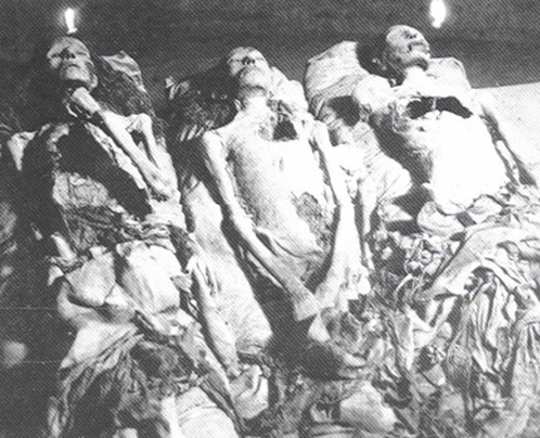 Мумии, обнаруженные в тайной камере гробницы фараона Эхнатона: по краям - кандидатки в Нефертити. Снимок был сделан в 1907 году при свечах